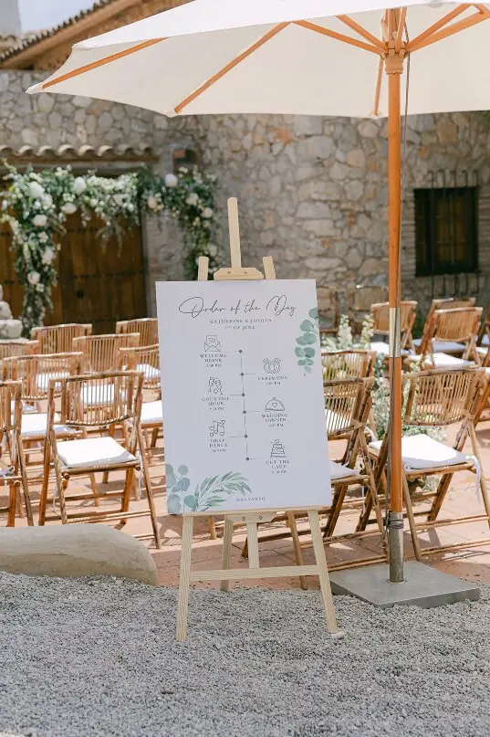Cartel con el orden del día junto a las sillas de la ceremonia en una boda al aire libre en Cataluña