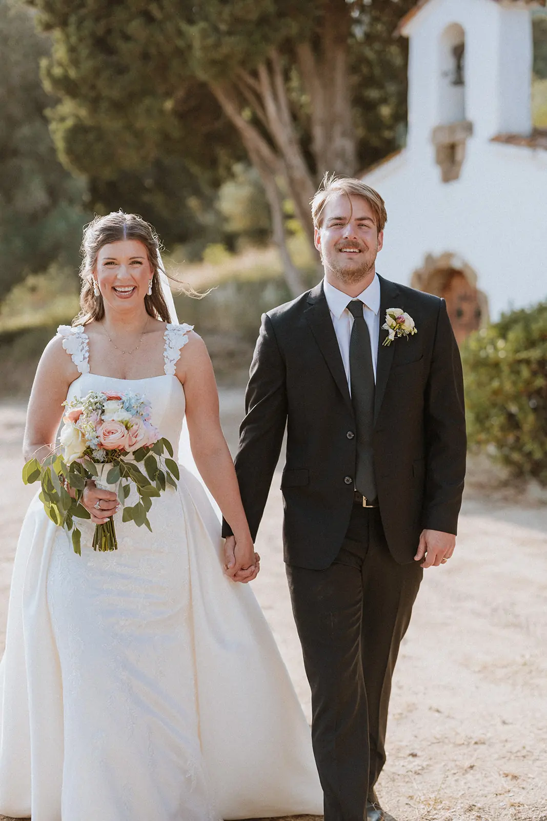 Una pareja recién casada paseando de la mano a la hora dorada en su boda en Cataluña