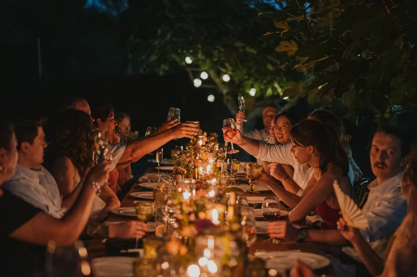 Invitados en una mesa larga iluminada con velas en una noche de verano en Cataluña