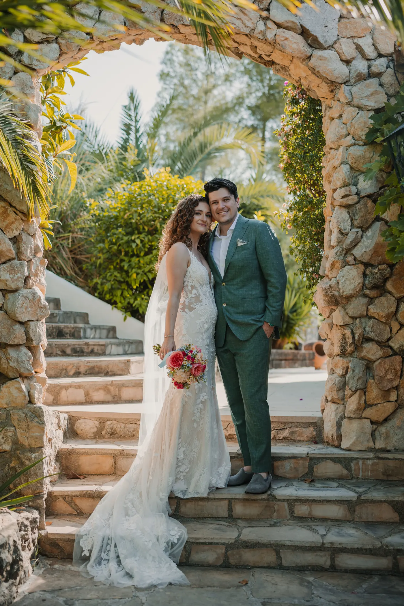 Una pareja bajo un arco de piedra en su boda íntima cerca de Barcelona