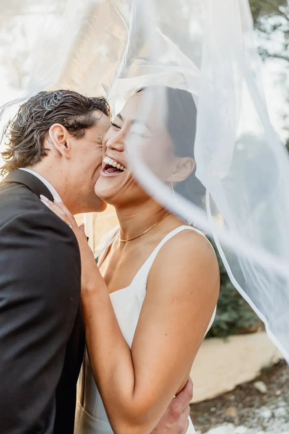 Una pareja riendo bajo el velo de la novia en su boda en Cataluña